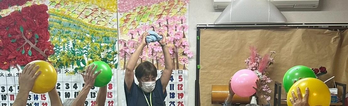 色とりどりのボールを頭の上に持ち上げる体操