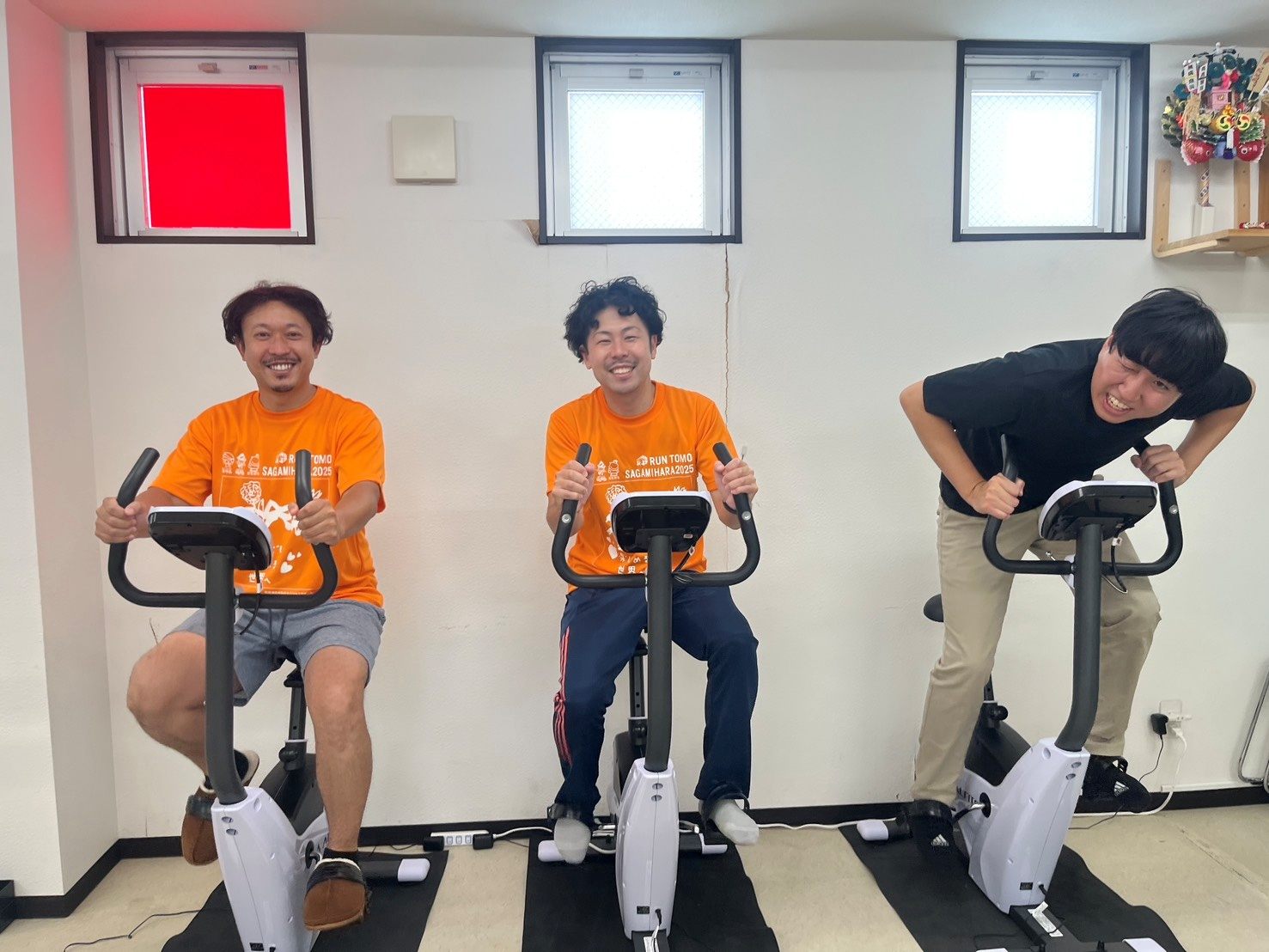 オレンジのTシャツで、並んで自転車こぎをするスタッフ