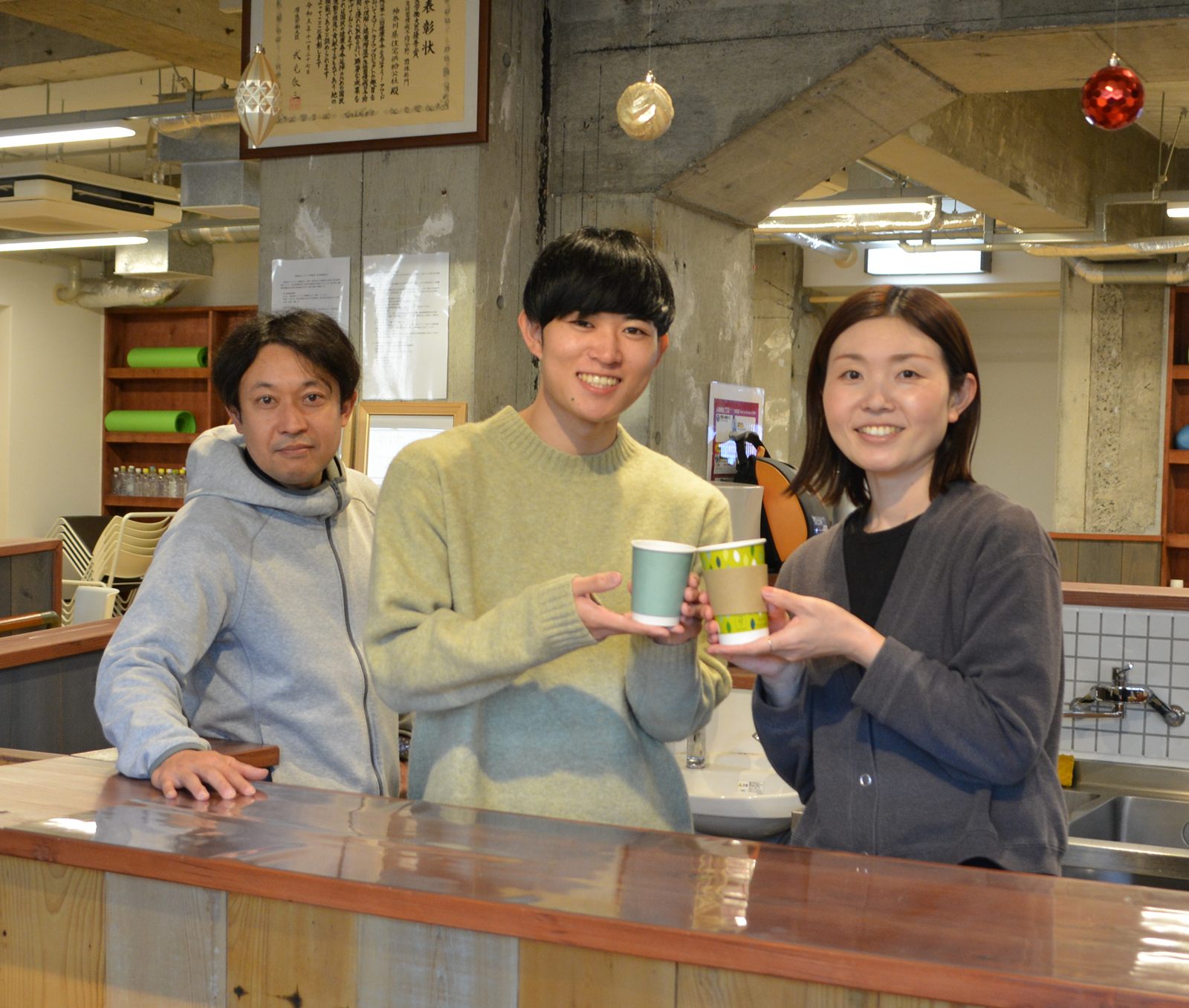 カウンターに並んで、カップを手に笑うスタッフ3人