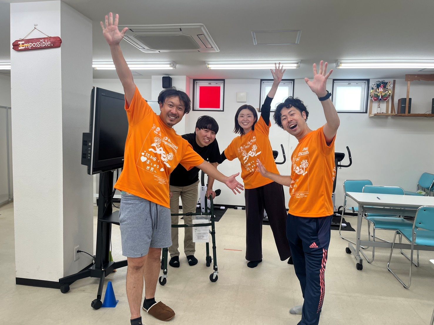 オレンジのTシャツで、思い思いのポーズをとるスタッフ