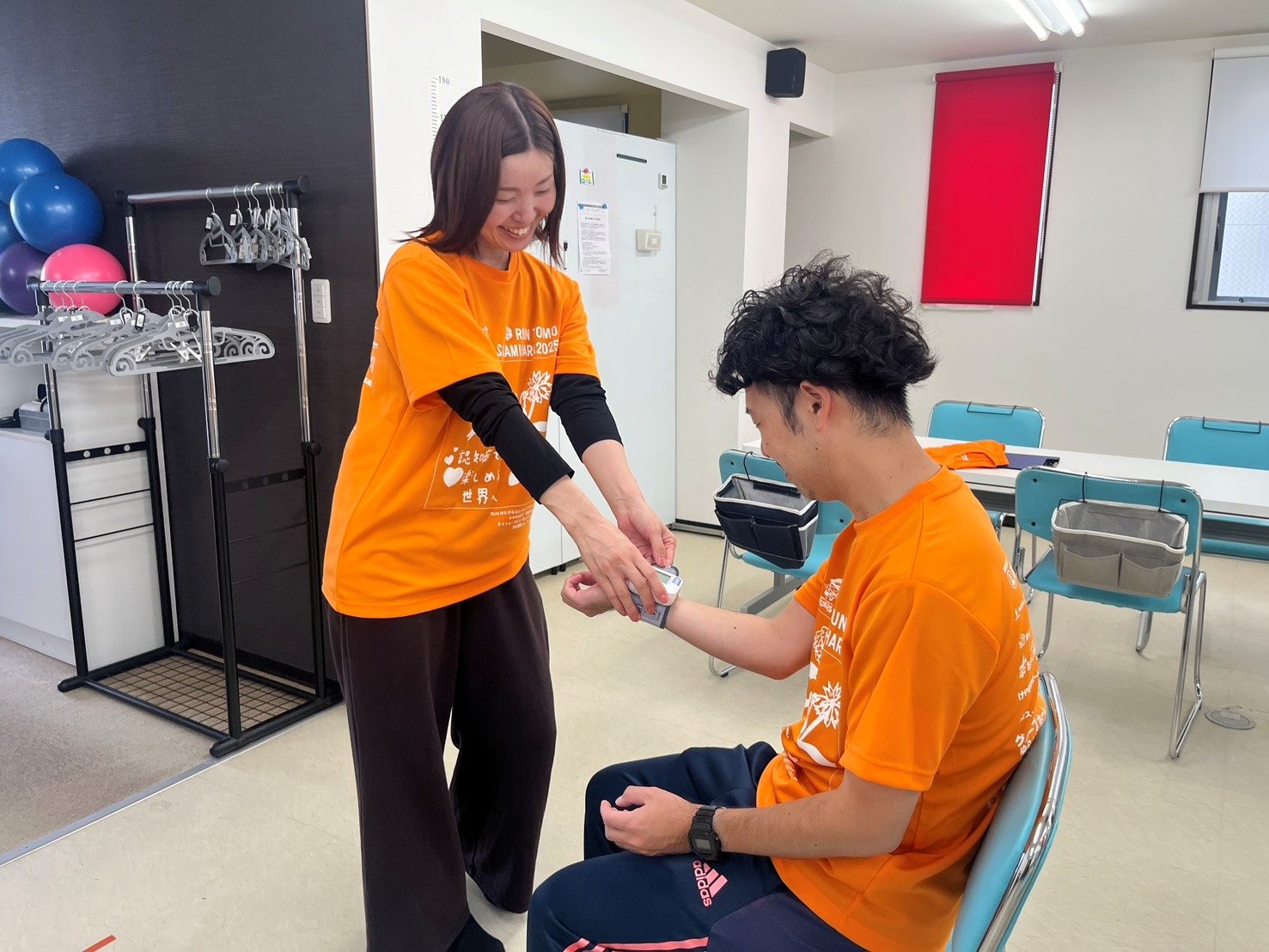 オレンジのTシャツで、腕の支え方を練習するスタッフ2人